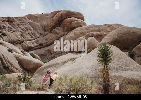 Two children staring up at tall rocks in Joshua Tree Stock Photo
