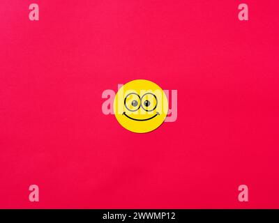 Smiling happy face emoticon on red background. Happiness, joy and positivity concepts. Stock Photo