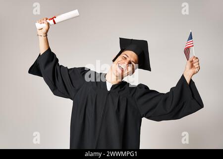 American student in graduate outfit happy to have completed his studies on grey background Stock Photo