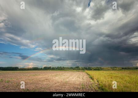 A rainbow in the cloudy sky over the fields, Nowiny, eastern Poland Stock Photo