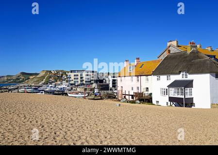 Boats in dry dock with the Ellipse building along the quayside and coastline to the rear, West Bay, Dorset, UK, Europe. Stock Photo