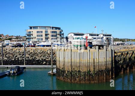 Boats in dry dock in the harbour with the Ellipse building to the rear, West Bay, Dorset, UK, Europe. Stock Photo