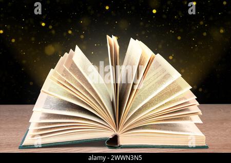 Fold-out book on a wooden surface against a dark background with bokeh. Stock Photo