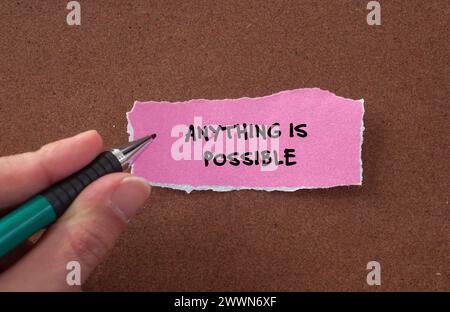 Anything is possible words written on pink torn paper piece with brown background. Conceptual symbol. Copy space. Stock Photo