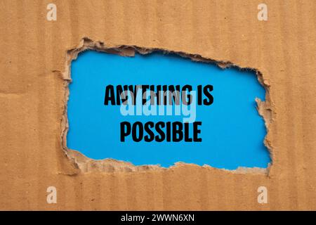 Anything is possible words written on torn cardboard paper with blue background. Conceptual symbol. Copy space. Stock Photo