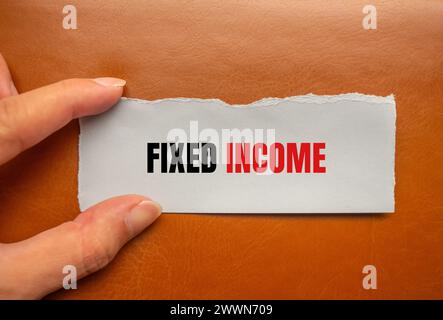 Fixed income words written on torn paper piece with brown background. Conceptual business symbol. Copy space. Stock Photo