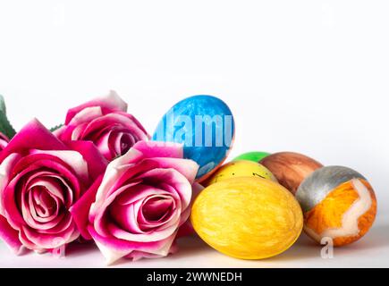 Colorful painted easter eggs and pink roses on white background, selective focus, close up Stock Photo
