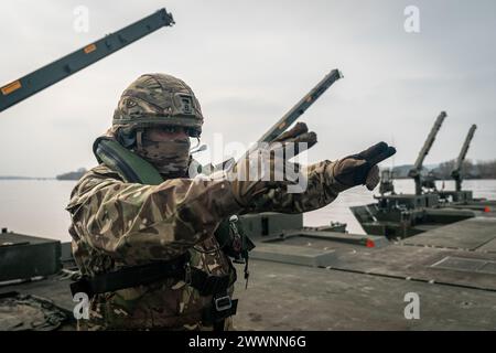 Photo Description:  A German soldier gives directions to his crew of an amphibious rig during an exercise, in Poland on March 2, 2024.  Exercise Background:  During Exercise Dragon-24 (DR-24) in Poland, NATO will test the Polish Armed Forces' response to potential crises, involving around 20,000 soldiers and 3,500 units of equipment from 9 NATO countries. The participants include: Poland; France; Germany; Lithuania;  Slovenia; Spain; Türkiye; United Kingdom and USA. The exercise will evaluate their ability to execute combat tasks across various domains, including land, air, sea, and cyberspace Stock Photo