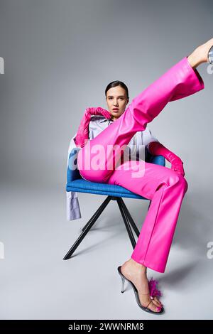 Confident brunette woman in trendy pink pants and shoes, sitting and kicking her leg up Stock Photo