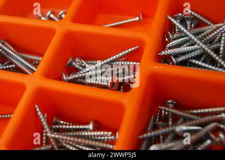 Red screw box with metallic screws. Close-up. Stock Photo