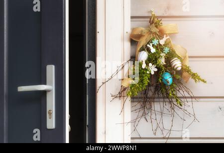 An open door and Easter decorations on wooden wall near the door. Happy Easter. Stock Photo