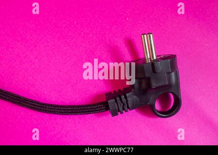 Black electric plug isolated on pink background. Top view, copy space. Stock Photo
