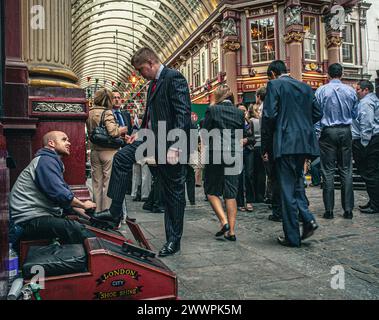 Shoe cleaner is polishing the shoes of a buissnesman in Leadenhall Market. Traditional shoe shine stall . Stock Photo