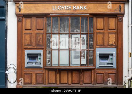 Twin ATM or cash machines outside of a Lloyds bank in Winchester, England.  Wooden window frame with historical display. March 2024. Stock Photo