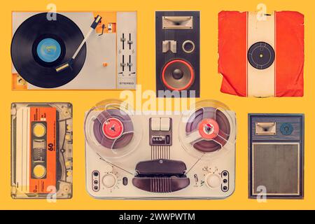 Collection of a vintage turntable, speakers, record, compact cassette and tape recorder on an orange background Stock Photo