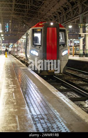 An illuminated modern train resting at the platform at night, showcasing urban transport with an almost empty passenger platform and gleaming lights. Stock Photo
