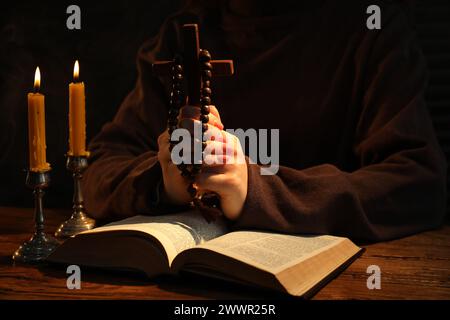 Woman praying at table with burning candles and Bible, closeup Stock Photo