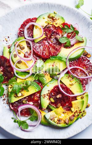 Blood oranges salad with avocado, pistachios and red onions, white background, close-up. Stock Photo