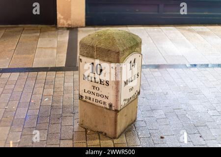 Vintage milestone indicating distance to London Bridge on a city street, symbolizing travel and history. Stock Photo