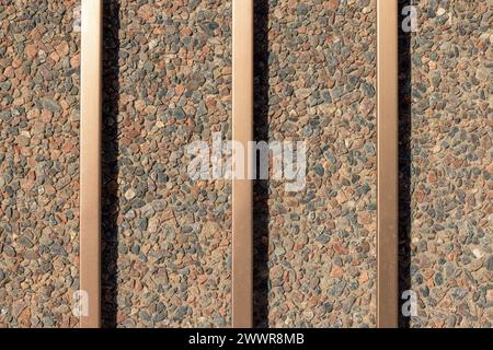 Concrete and pebble wall background with bronze metal bars Stock Photo