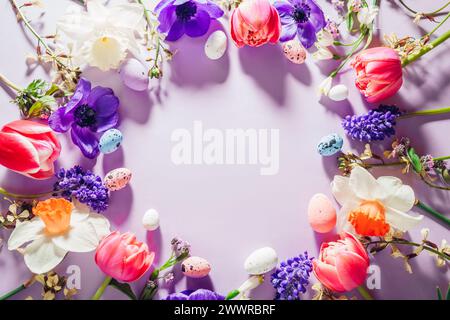 Happy Easter mockup. Easter eggs background with spring pink purple flowers flat lay, empty center. Greeting card banner with space. Top view Stock Photo