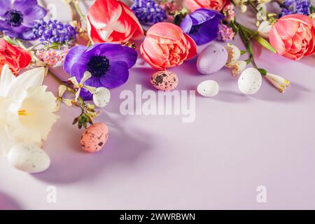 Easter decor mockup. Easter eggs floral background with spring pink purple flowers flat lay. Greeting card with tulips, daffodils. Space Stock Photo