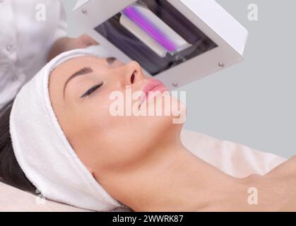 The cosmetologist uses the Wood Lamp for detailed diagnosis of the skin condition. The device detects the presence of skin diseases or inflamed areas. Stock Photo