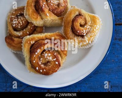 Cinnamon buns on white plate on blue table Stock Photo