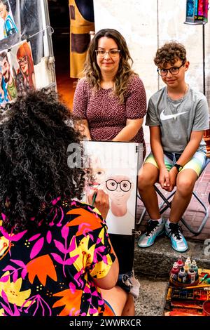 Tourists Having Their Portraits Drawn At The San Telmo Sunday Market, Buenos Aires, Argentina. Stock Photo