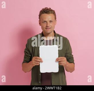 A man is holding a white card in his hand. The card is rectangular and has a white background. The man is smiling and he is happy Stock Photo