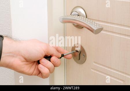 Man fixing door lock in room with screwdriver, Close-up of door repair, new gateway repair. High quality photo Stock Photo