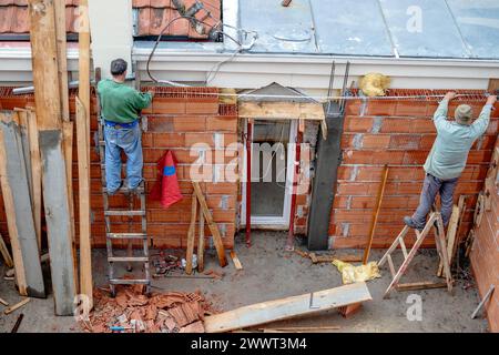 Construction workers are checking the measurement of the wall of the house they built from building blocks. Stock Photo