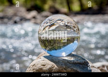 Wildbach in den Bergen mit Alpenpanorama im Hintergrund spiegelt sich in einer Glaskugel. Schmelzwasser führende Wildbäche in den Alpen wie zum Beispiel die Breitachklamm sind eine interessante Sehenswürdigkeit und beliebtes Ausflugsziel - auch an Tagen mit schlechtem Wetter. Es gibt verschiedene Wandertouren entlang solcher Gewässer die dann teils über Stege entlang von Stromschnellen und kleinen Wasserfällen führen. Raum Oberstdorf Bayern Deutschland *** Torrent in the mountains with a panoramic view of the Alps in the background reflected in a glass sphere Torrents carrying meltwater in the Stock Photo