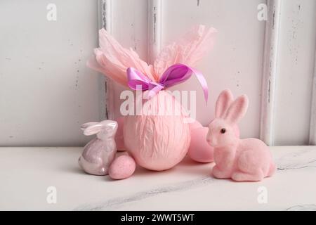 Painted and chocolate Easter eggs wrapped in paper with bunnies on white grunge background Stock Photo