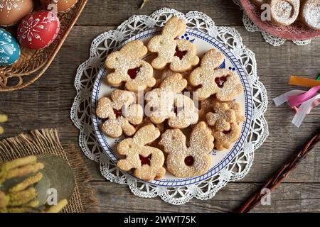 Homemade Linzer cookies in the shape of bunnies and chicken with Easter eggs decorated with wax in the background Stock Photo