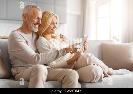 Affectionate couple using tablet on couch Stock Photo