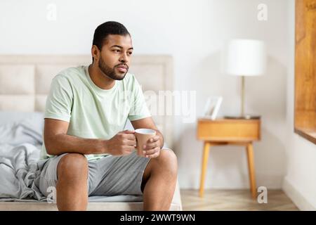 Man sitting with coffee in bedroom Stock Photo