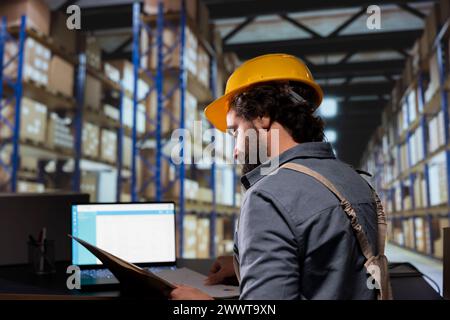 Distribution engineer works on transportation and logistics details with file documents and supply contracts. Warehouse employee managing stock production and distribution, industrial depot. Stock Photo