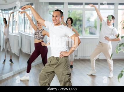 Cheerful Asian fitness instructor leading Zumba class Stock Photo