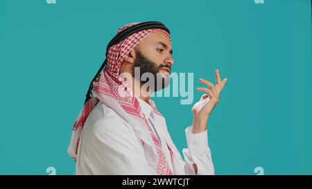 Middle eastern man being puzzled and thinking about solution, being interested about a subject and trying to find answer. Young adult being pensive in studio, wondering about new idea. Stock Photo