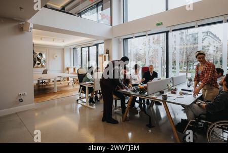 A multicultural group of colleagues collaborates in a well-lit, contemporary office setting, fostering teamwork and creativity. Stock Photo