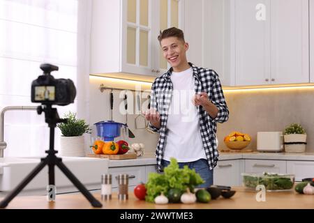Smiling food blogger explaining something while recording video in kitchen Stock Photo