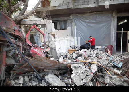 Beijing, China. 26th Mar, 2024. A Palestinian gives a haircut to a man near the rubble of a destroyed building in Deir al-Balah in the central Gaza Strip, March 24, 2024. Credit: Xinhua/Alamy Live News Stock Photo