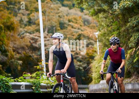 young asian couple cyclists riding bike on rural road Stock Photo