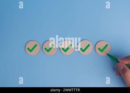 hand holding pen check mark on blue background. Business quality target strategy marketing concept. Stock Photo