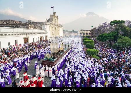 Antigua, Guatemala. 24th Mar, 2024. Catholic penitents carry the massive processional float as it moves around the Central Plaza with the Agua Volcano and the Cathedral of Saint James San José during the 20-hour long Palm Sunday La Reseña procession, March 24, 2024 in Antigua, Guatemala. The opulent processions, detailed alfombras and centuries-old traditions attract more than 1 million people to the ancient capital city. Credit: Richard Ellis/Richard Ellis/Alamy Live News Stock Photo