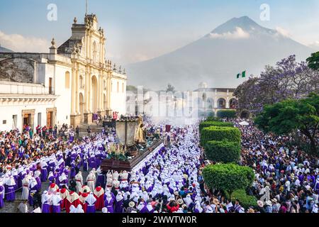 Antigua, Guatemala. 24th Mar, 2024. Catholic penitents carry the massive processional float as it moves around the Central Plaza with the Agua Volcano and the Cathedral of Saint James San José during the 20-hour long Palm Sunday La Reseña procession, March 24, 2024 in Antigua, Guatemala. The opulent processions, detailed alfombras and centuries-old traditions attract more than 1 million people to the ancient capital city. Credit: Richard Ellis/Richard Ellis/Alamy Live News Stock Photo