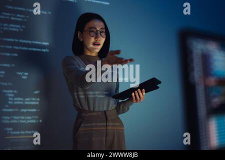 asian woman developer presentation about coding software data with devops team at night in office Stock Photo