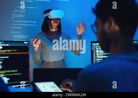 asian and Indian developer devops team testing  virtual reality coding and presentation  with ai prompt  at night in office Stock Photo