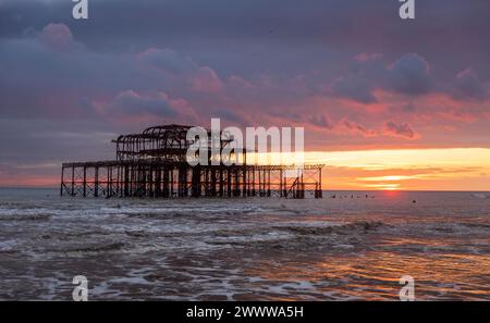 Sunset behind the ruins of the west pier on the Brighton coast east Sussex south east England UK Stock Photo